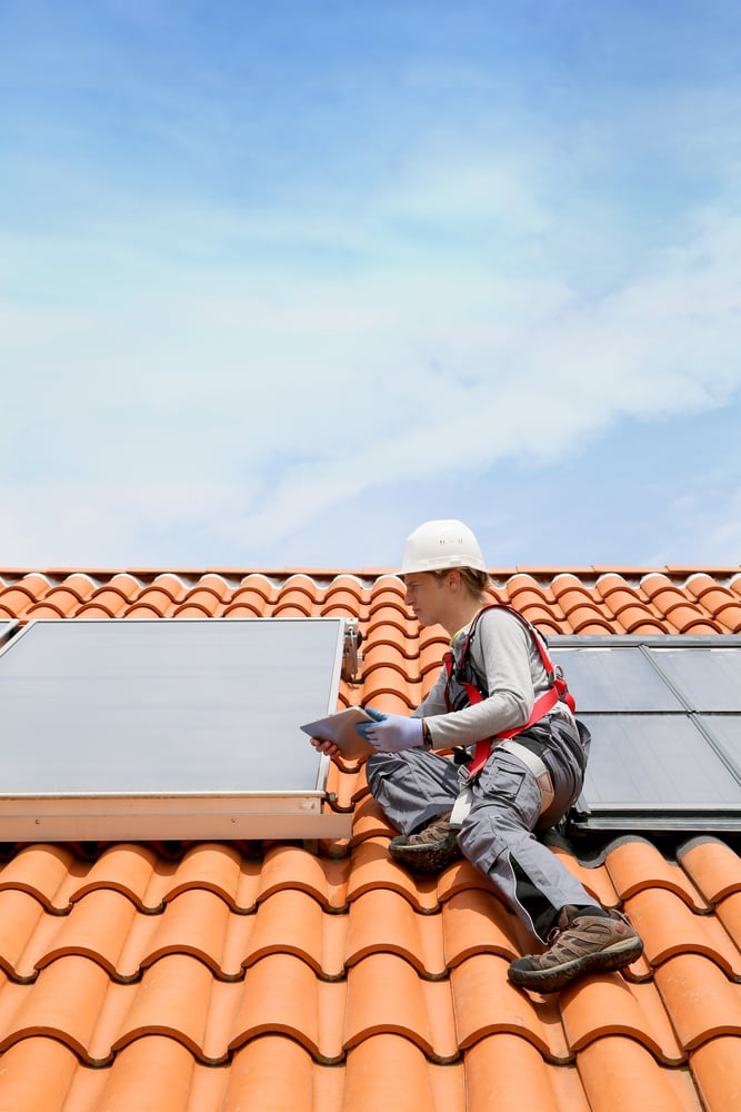 Man on roof top checking on solar panel installation