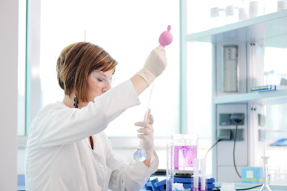 Medical woman measuring liquid in erlenmeyer in lab